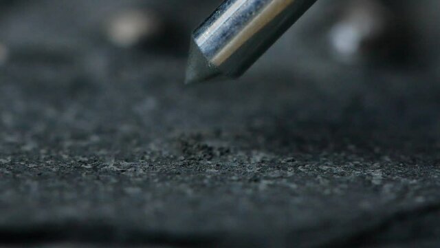 Macro shot of pneumatic pen breaking up rock and revealing an ammonite fossil