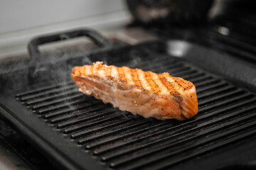 Cooking salmon fillet steak on grill with smoke