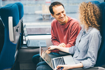 Two colleagues working on a train. Business, diversity, travel and transportation concept.