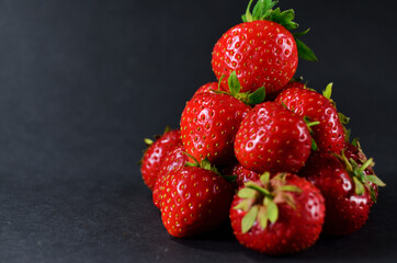 mountain of ripe red strawberries lies on a black table