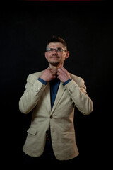 mature actor in glasses straightens shirt collar smiling performing at audition against stage black background closeup