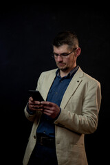 mature actor in glasses checks black smartphone screen in hand standing on studio stage at audition close view