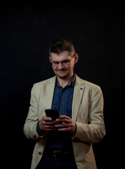 smiling actor with tree-day stubble in glasses sends message by smartphone standing on studio stage at audition closeup