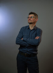 proud guy in grey shirt and denim jeans crosses hands and poses for photo shoot in studio at audition close view
