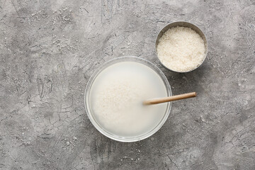 Bowls with rice and water on grey background