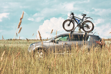 Bicycle transportation - fastened Bicycle on the roof of a car against a beautiful sky driving in...