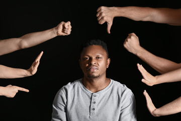 People bullying African-American man on dark background. Stop racism