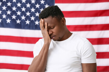 Sad African-American man near national flag of USA. Stop racism