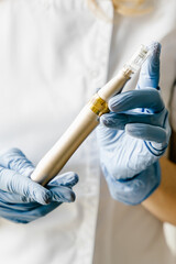 Golden dermapen for mesotherapy on cosmetologist's hands in blue gloves. Cosmetology product. 