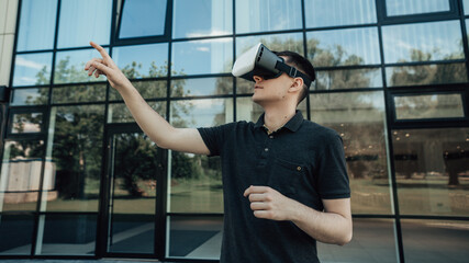 Close up portrait of man gesturing while playing games in virtual reality glasses. Future hobbie, entertainment. Male in VR headset, helmet, testing new interface and software.