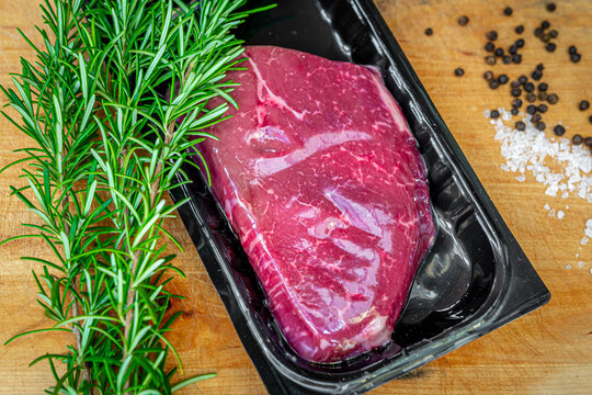 Beef steak in vacuum skin packaging and spices on wooden chopping board