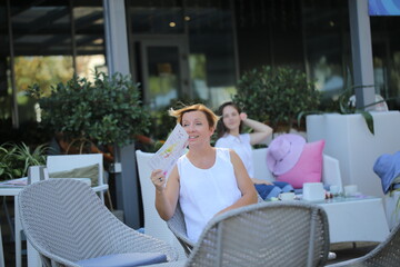 two girls are sitting in a cafe drinking coffee and taking selfies