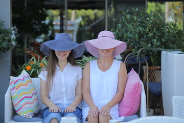 two girls are sitting in a cafe drinking coffee and taking selfies