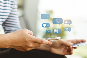 Hands of a woman using mobile phone and hold credit card with notification icons of shopping, message, comment and star , above smartphone screen.