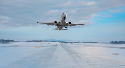 Fototapeta na wymiar Commercical white airplane fly up over take-off runway the (ice) snow-covered airport- Norway