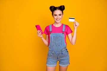 Portrait of her she nice-looking attractive lovely cheerful cheery confident girl using cell bank card wireless order app isolated on bright vivid shine vibrant yellow color background