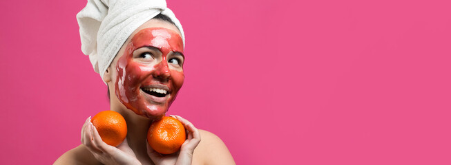 Beauty portrait of woman in white towel on head with red nourishing mask on face. Skincare cleansing eco organic cosmetic spa relax concept. A girl stands with her back holding an orange mandarin.