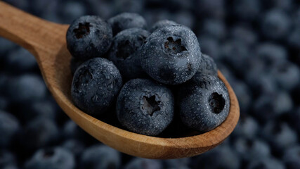 blueberries with water drops in wooden spoon and blueberry on background
