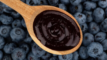 blueberry puree in wooden spoon and blueberries on background