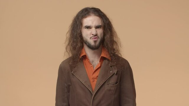 Yeah sure, of course. Charismatic funny and weird hipster guy with beard and curly long haircut, nod in approval and mumbling as if agree or approve something, encourage do it, beige background