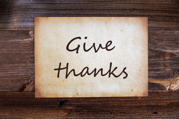 Old Grungy Paper With English Text Give Thanks. Wooden Background
