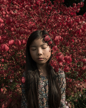 Portrait of teenage girl with eyes closed standing by bush
