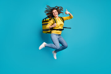 Fototapeta na wymiar Full length body size view of nice attractive cheerful cheery glad wavy-haired girl jumping bringing takeaway package showing thumbup isolated bright vivid shine vibrant blue color background