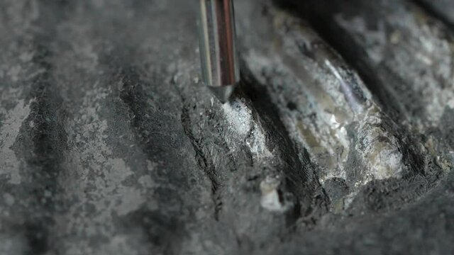 Macro shot of pneumatic pen breaking up rock and revealing an ammonite fossil