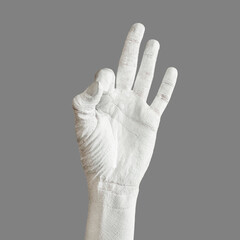 Hand is painted roughly white. Hand gesture isolated on gray background. Bold body art painting.