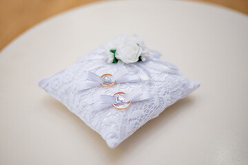 wedding rings on a white lace pillow