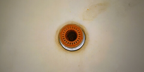 old rusty drain with orange coverage in outdated bath