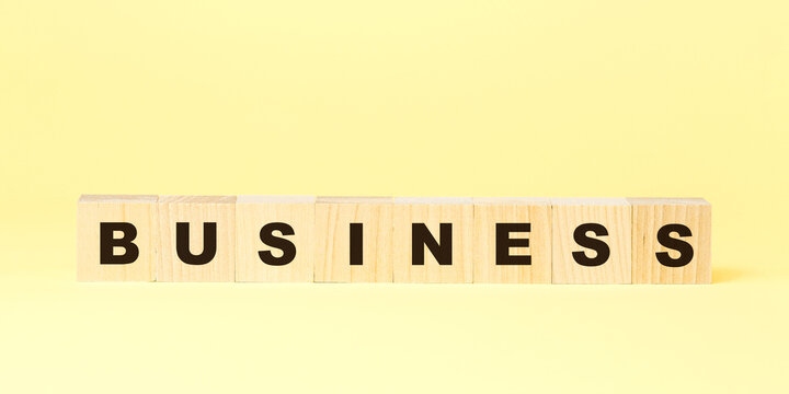word business made with wooden blocks on yellow background