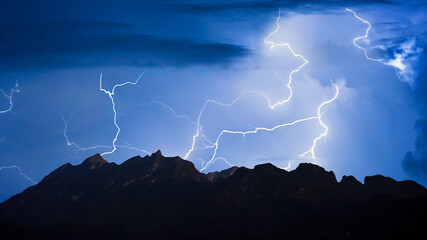 Panorama view of thunder storm lightning strike over mountain with dark cloudy sky background at...