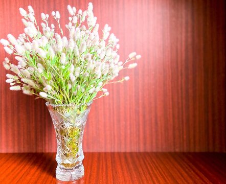 Crystal vase with a bouquet of wildflowers on an abstract wooden background.Free space.