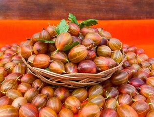 Ripe red gooseberries in a basket on an abstract surface. The concept of proper nutrition, agriculture. Free space.