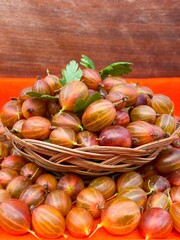Ripe red gooseberries in a basket on an abstract surface. The concept of proper nutrition, agriculture. Free space.