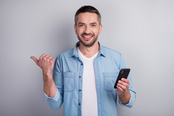 Close-up portrait of his he nice attractive content cheerful cheery guy using digital gadget demonstrating ad advert advice recommend copy space isolated over gray light pastel color background