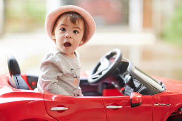 Surprised baby girl in toy car