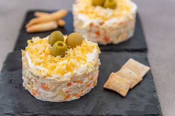Russian traditional salad Olivier with vegetables on grey background