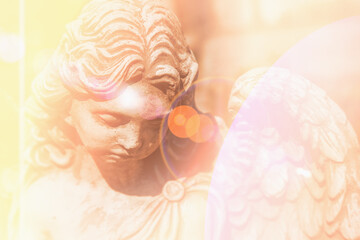 Beautiful angel with wings in sunshine. Ancient stone statue, fragment.