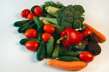 Fresh vegetables on a white background. Broccoli, zucchini, tomatoes, cucumbers, carrots, peppers, dill. Healthy organic food for vegetarians. Ingredients for summer salad.