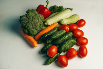 Fresh vegetables on a white background. Broccoli, zucchini, tomatoes, cucumbers, carrots, peppers, dill. Healthy organic food for vegetarians. Ingredients for summer salad.