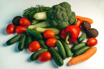 Fresh vegetables on a white background. Broccoli, zucchini, tomatoes, cucumbers, carrots, peppers, dill. Healthy organic food for vegetarians. Ingredients for summer salad.