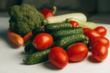 Fresh vegetables on a white background. Broccoli, zucchini, tomatoes, cucumbers, carrots, peppers, dill. Healthy organic food for vegetarians. Ingredients for summer salad.