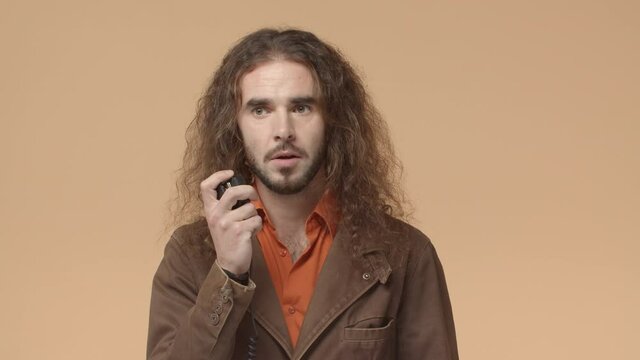 Come again. Serious bearded hipster, male with long curly hair, listening to coworker via remote radio set, dispetcher receive call on transmitter and saying yes, copy that, approve give permition
