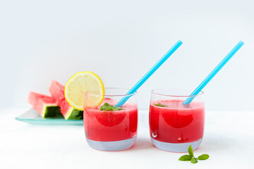 Watermelon smoothie in clear glass glasses with lemon slices on a light background. The concept of light, summer, healthy food.