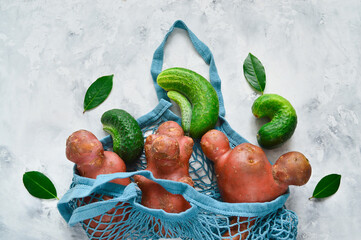 Fresh ugly cucumbers and potatoes on a concrete gray background. Trendy ugly vegetables. Imperfect...