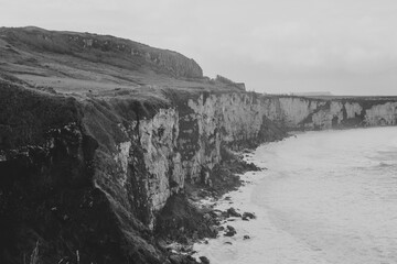 Black and White landscape photo of an ireland cliff with the atlantic ocean mountains on the background 