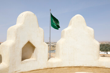 Flag of Saudi Arabia waving in the wind, In the foreground the battlements of a castle