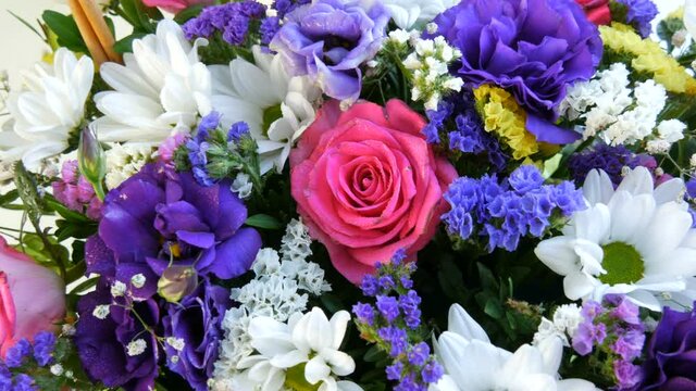 A beautiful stylish bouquet of various multi-colored flowers of daisies, roses, dried flowers. Festive bridal bouquet of white, pink, blue, purple, yellow flowers.